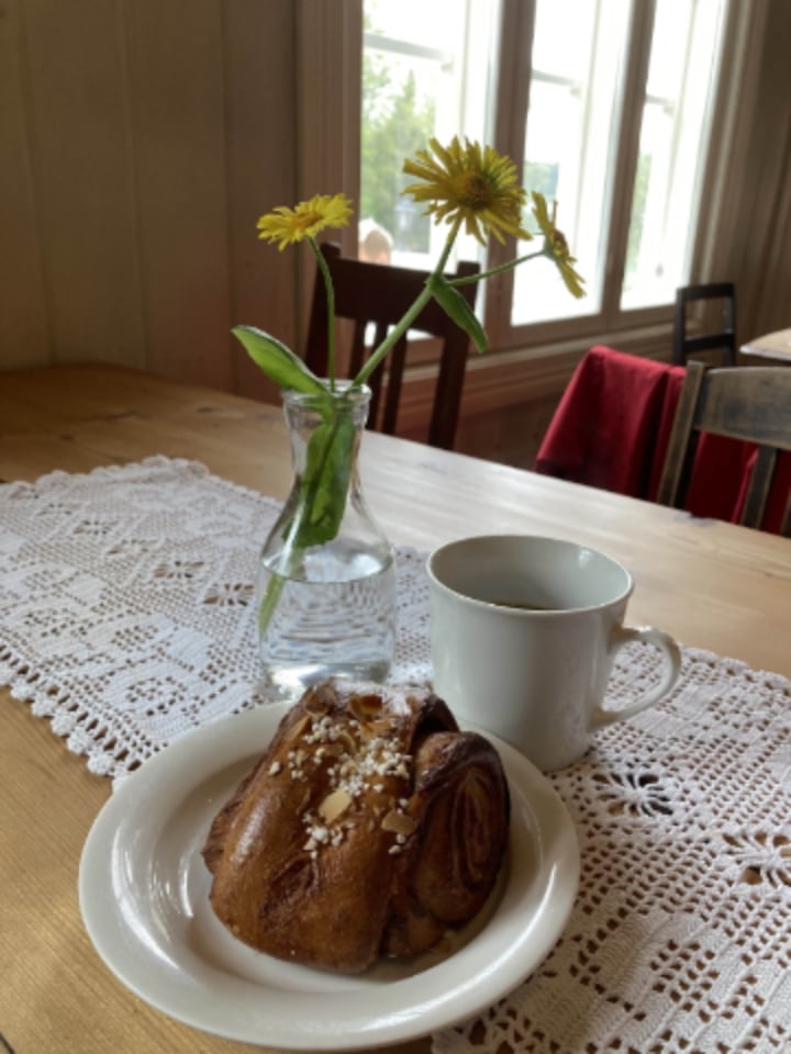 Eine Zimtschnecke, ein Kaffee und gelbe Blumen